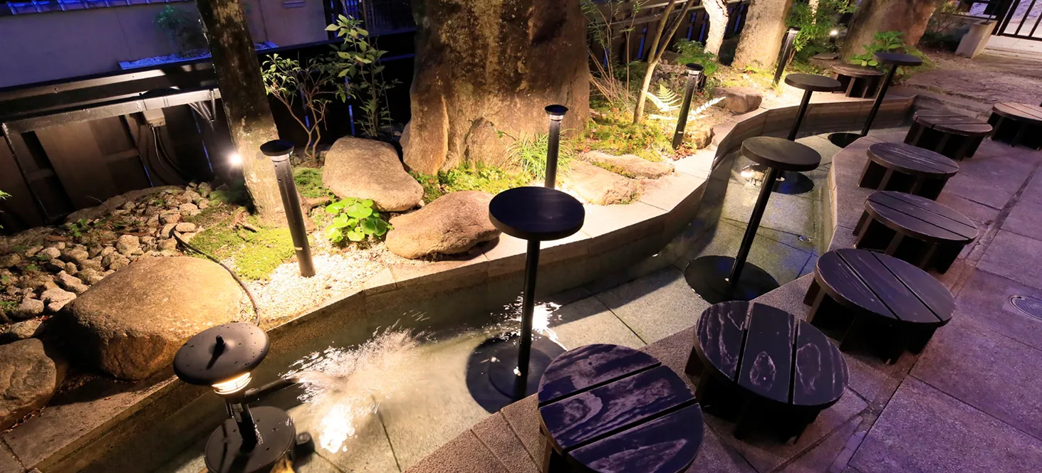 夜の光に照らされた足湯と丸型の椅子が並ぶ風景